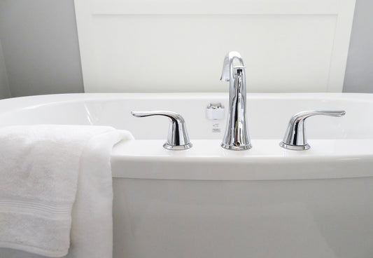 White bath tub with silver faucet and handles and a white towel